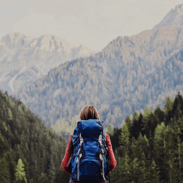 A female backpacker facing a view of mountains.