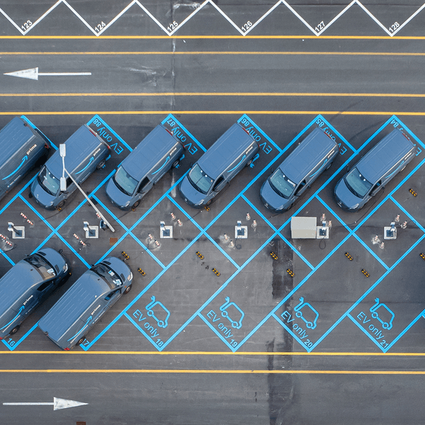 Aerial view of Amazon delivery electric van fleet charging in parking lot