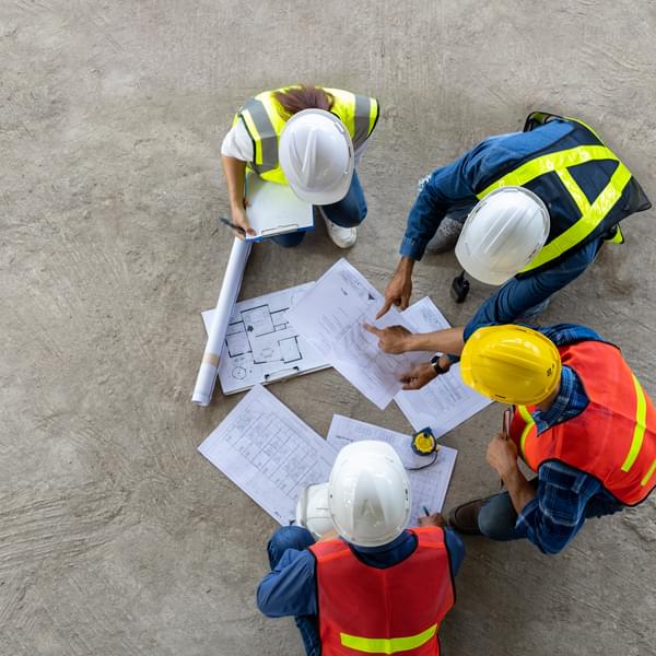 Energy contractors huddled together over blueprints.