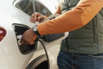 African American man inserting plug into the electric car charging socket