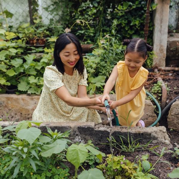 Mother and daughter watering garden in the yard.