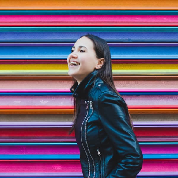 Happy young urban woman laughing while standing outside in the city