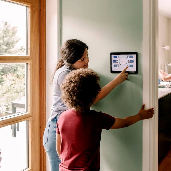 Sister and brother using home automation device while standing in hallway
