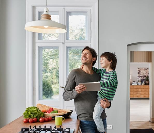 Dad and son using home automation device in kitchen