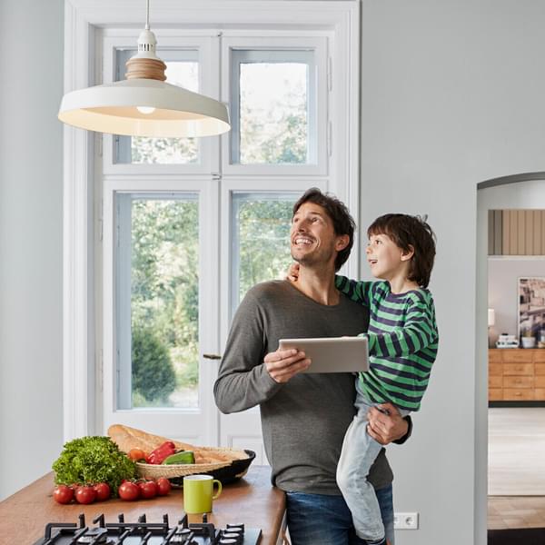 Dad and son using home automation device in kitchen