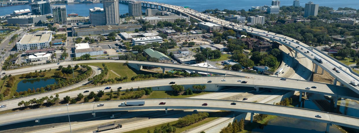 aerial view of a busy freeway interchange with roads crossing over each other and cars zooming by