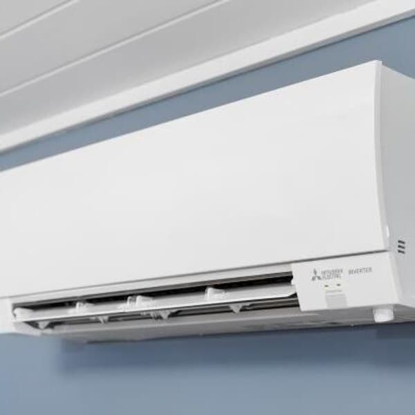 air conditioner unit on affixed on a blue wall of a bedroom