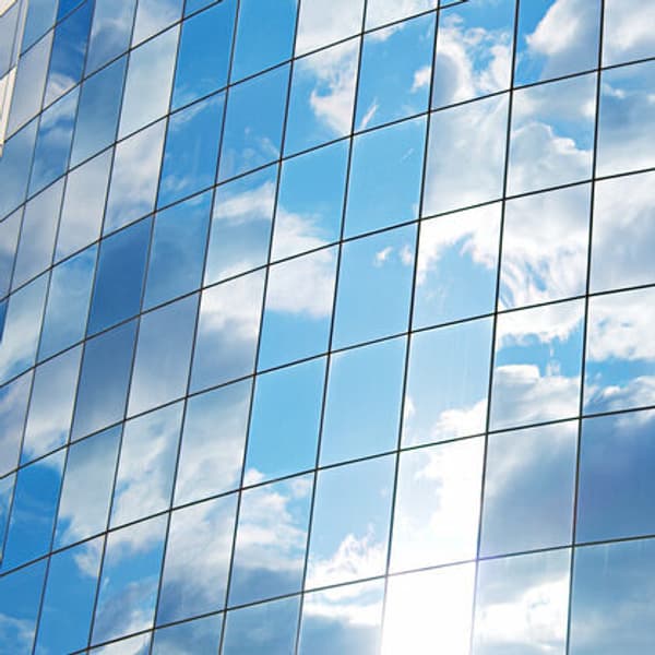 windows of a financial building reflecting a blue and cloudy sky