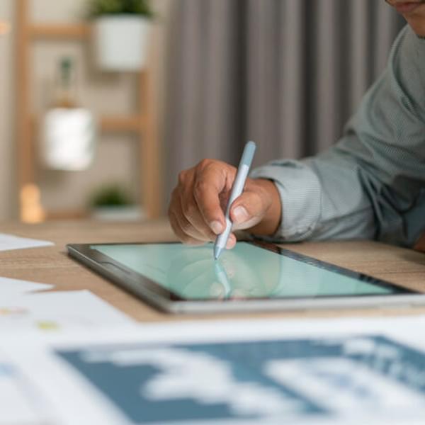 close up of someone's hand writing on a tablet with a pen