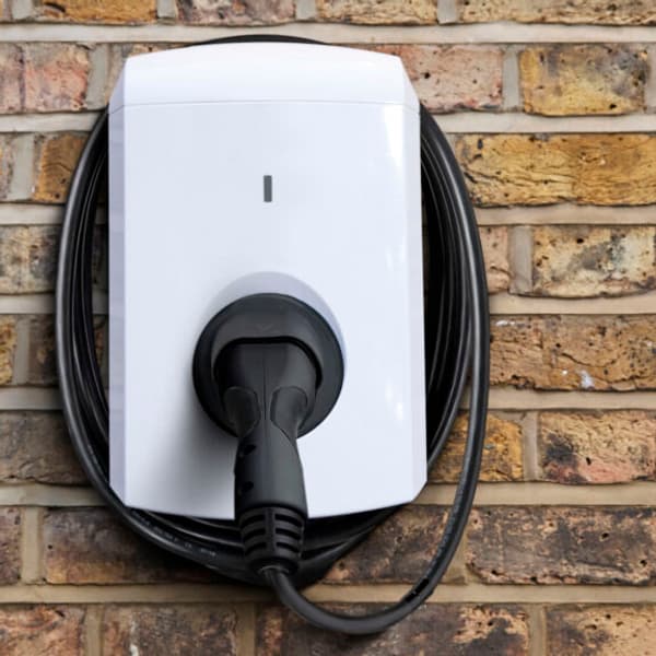 close up of an electric vehicle charger connected to the the side of a house