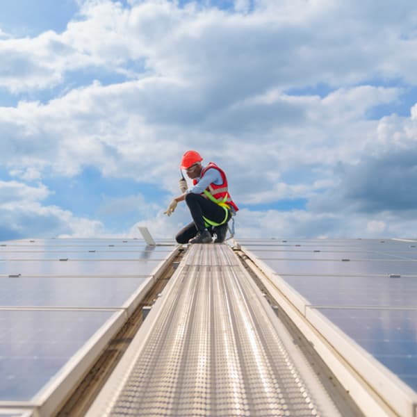 electrical engineer working on solar panels wearing a hardhat and orange vest