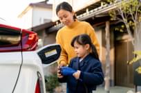 Young girl helping her mom to charge their electric car at home