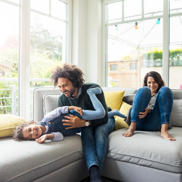 father and mother playing with their small child on the couch in their house