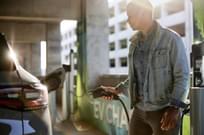 man at a charging station plugging in his electric vehicle to the charger