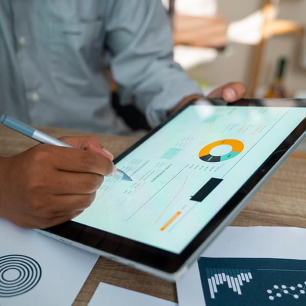 close up of a mans hands holding a tablet with analytics on the screen
