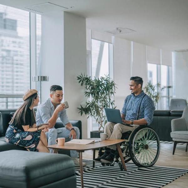 three people having a casual meeting around a coffee table in an offices communal workspace