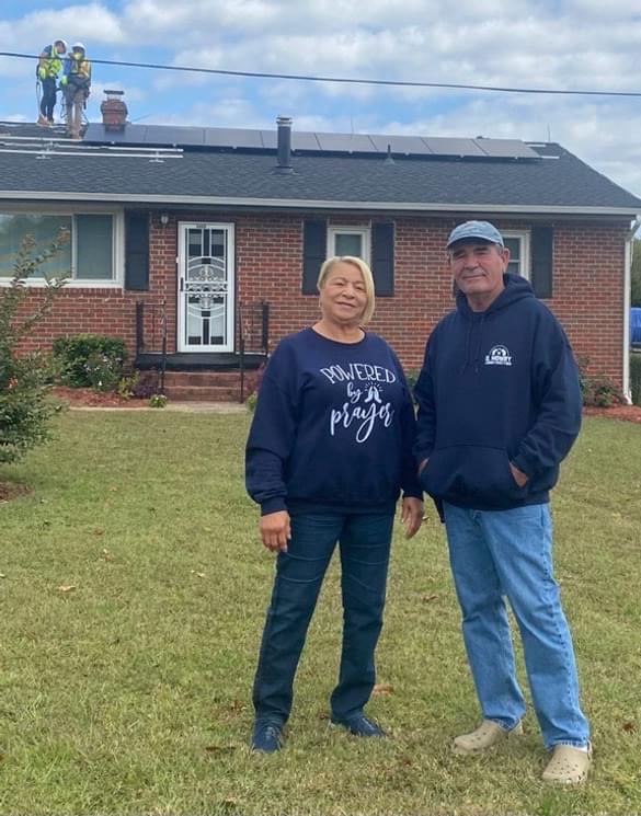 A residential utility customer poses in front of her home with new solar panels
