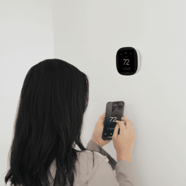 woman syncing her smart thermostat with her cellphone
