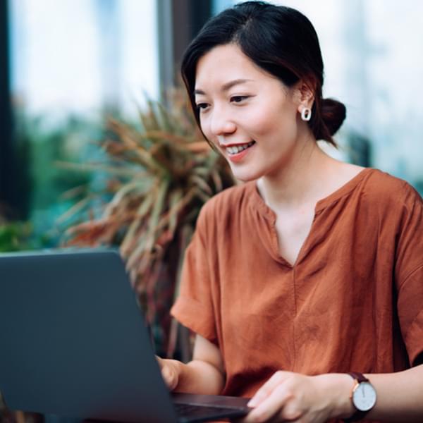 smiling young woman sitting outside working on her computer