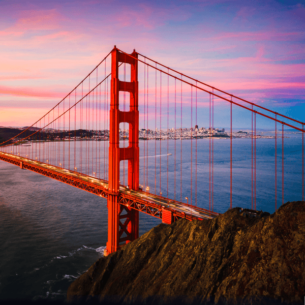 sunset photo of the golden gate bridge with a pretty pink and blue sky in the background