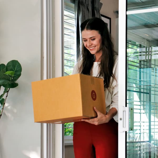 woman smiling while holding a package that was delivered to her house