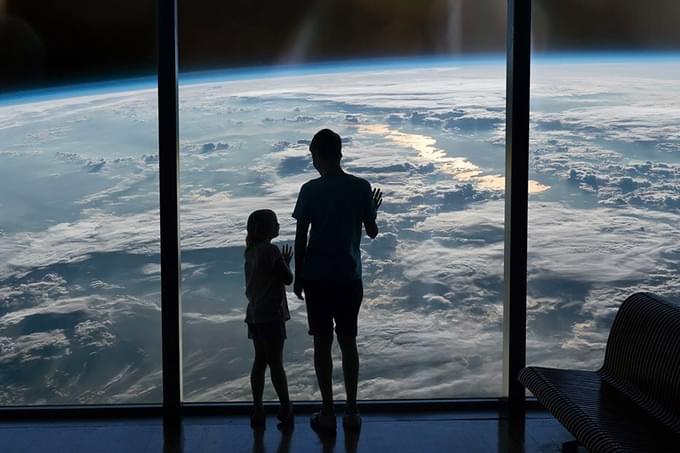 People look through window to Earth