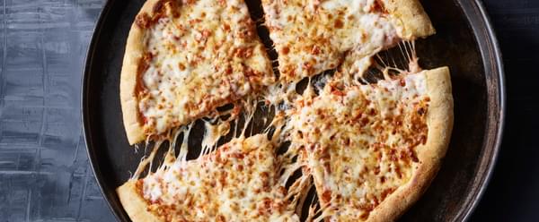 A hand grabs a slice of cheesy margherita pizza from a plate