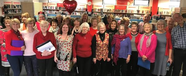 A group of people in a library setting smiling for a photo
