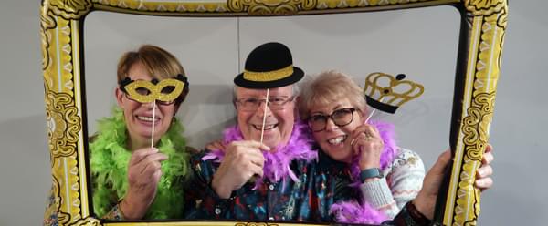 Three smiling people pose behind an inflatable photo frame