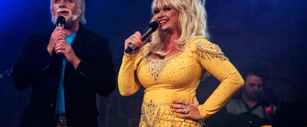 Performers impersonating Kenny Rogers and Dolly Parton stand singing on stage together
