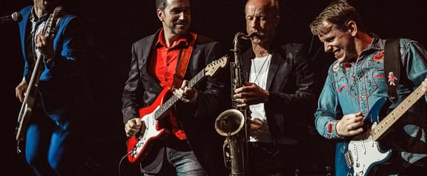 Member of dire streets playing instruments on stage