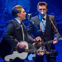 Two male cast members of "Walk Right Back" sing and play guitars