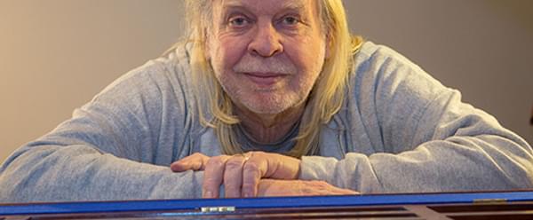 An image of Rick Wakeman leaning on a piano