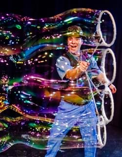 A man pulling four giant bubbles at the same time
