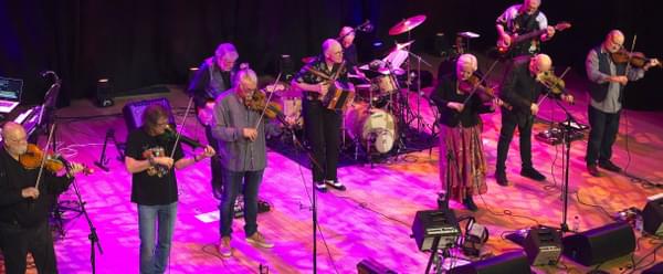Members of the band Feast of Fiddles line up on stage playing their instruments