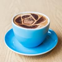 A close up image of a cappuccino in a round cup and saucer