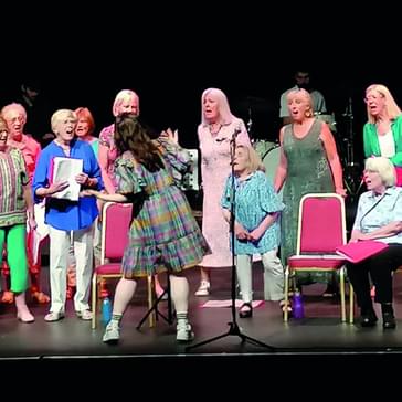 A wide angled view of The Roses' choir on stage