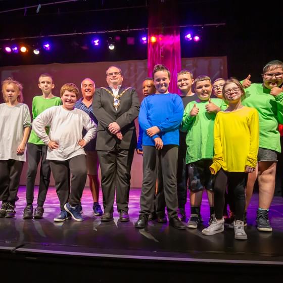 A group of children line up on stage to take a bow after a successful performance