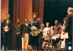 Princess Anne holding a bouquet of flowers on stage surrounded by people