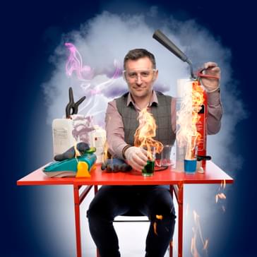 An image of Mark Thompson seated at a table surrounded by exciting science equipment