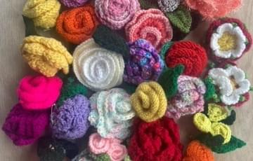 A cluster of knitted rose brooches in a variety of colours