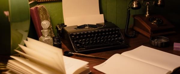 A vintage typewriter and telephone sit on a desk