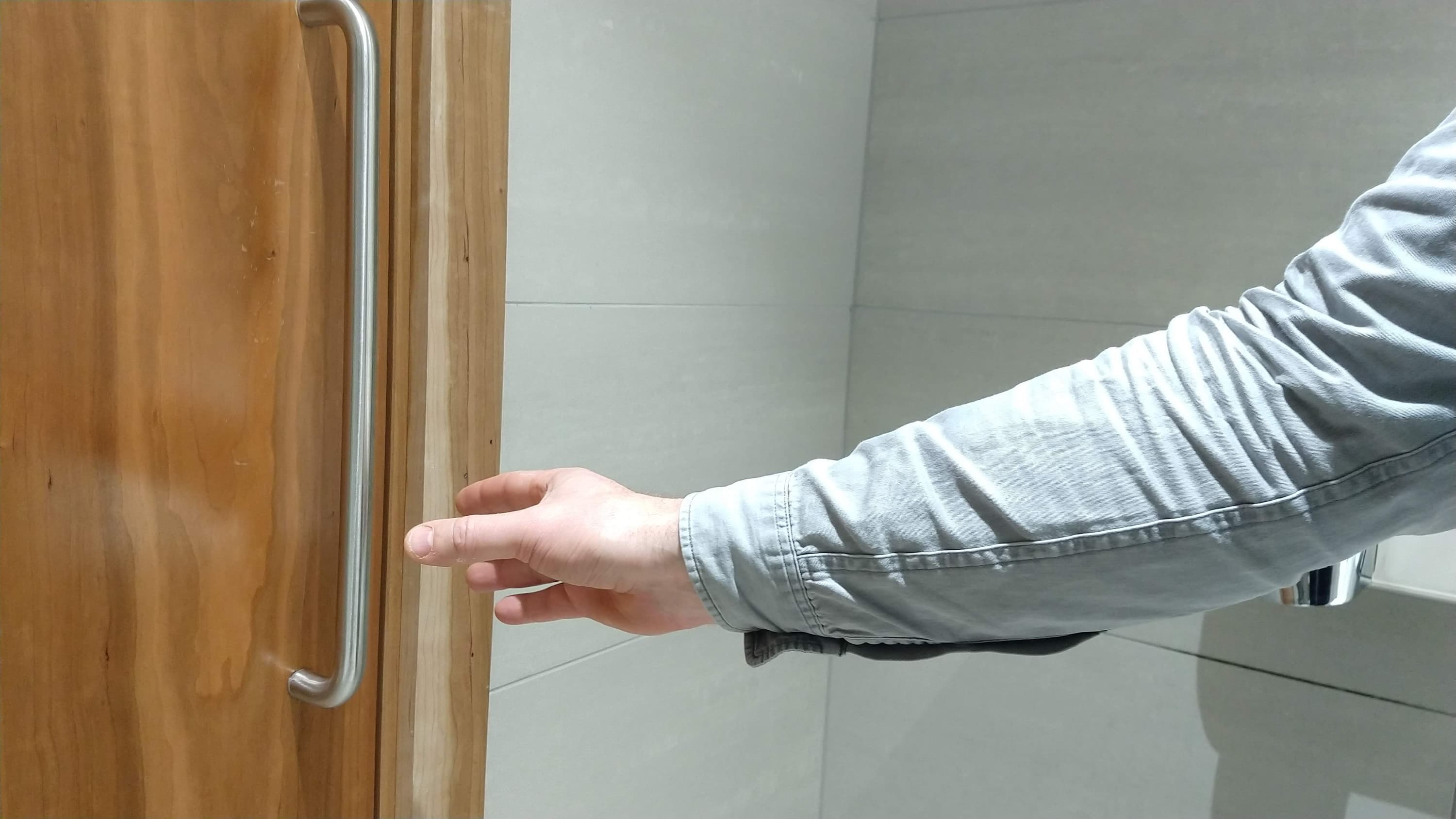 A man’s hand reaching out to grab a door handle