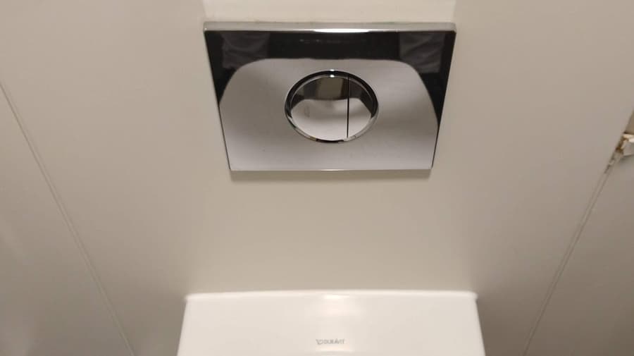 View of toilet flush buttons with the toilet seat down.