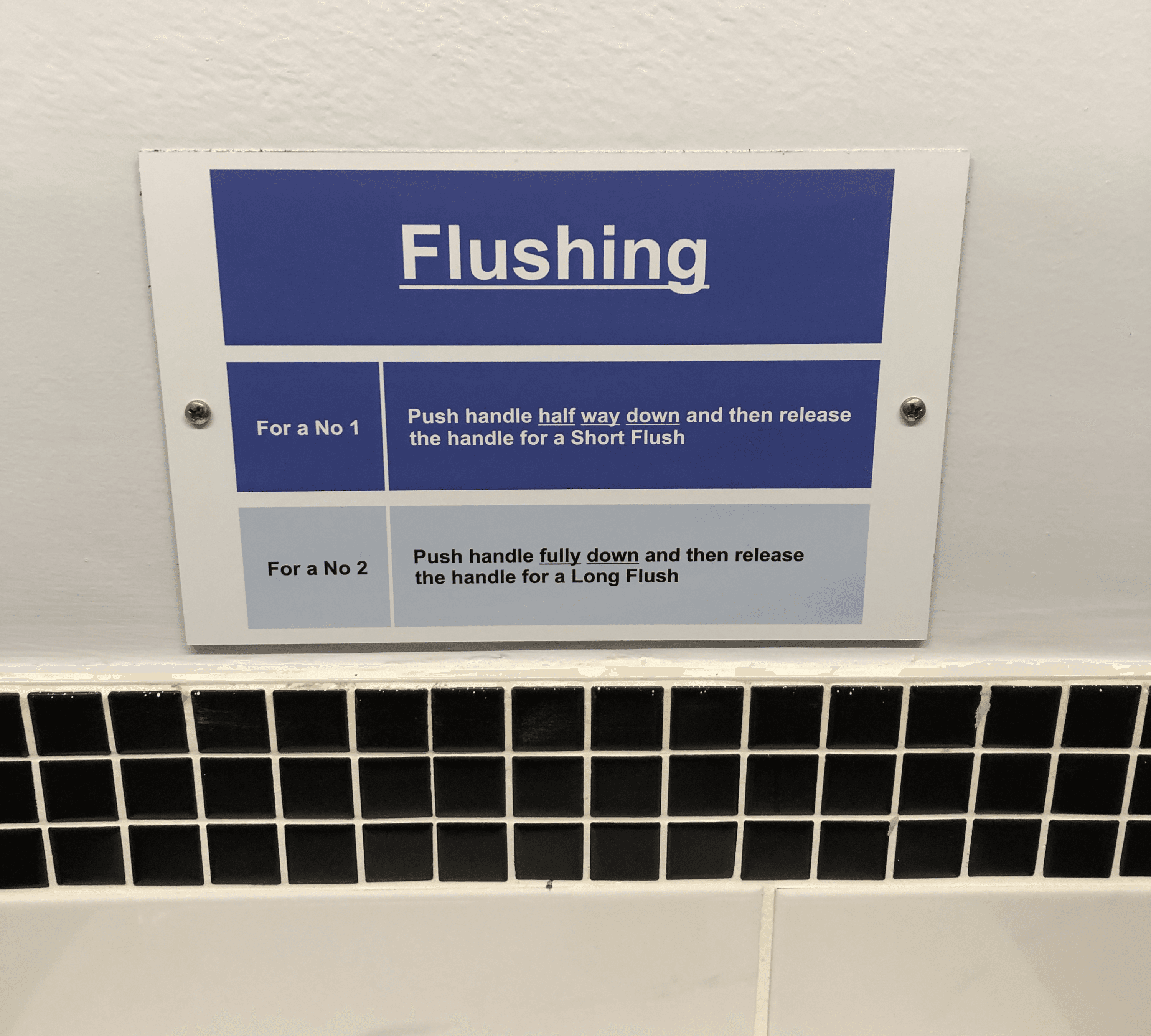 A sign providing instruction how to use the flushing system. For a no 1, pull the handle half-way down; for a no 2 pull the flush fully down.