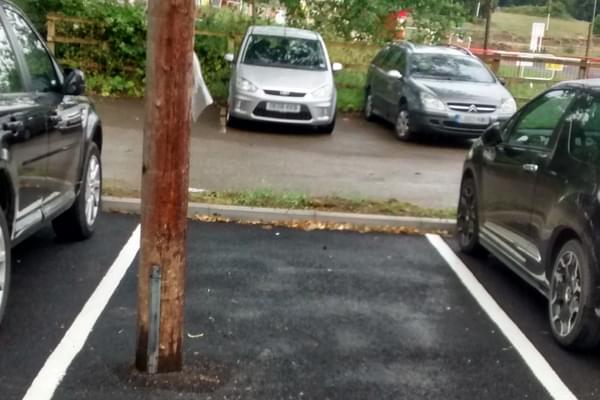 An empty parking bay (delineated by white lines) between two parked cars. The problem is there is a telegraph pole situated in the parking bay making it an accident waiting to happen.