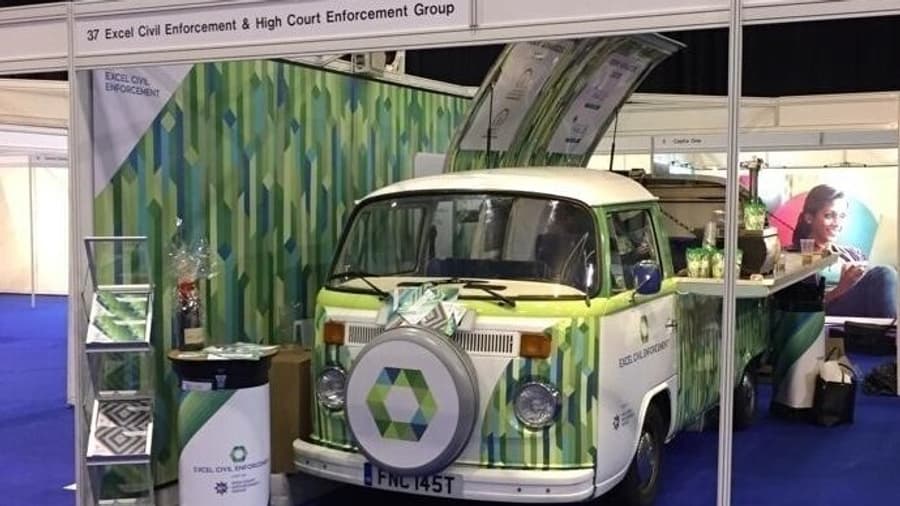 Classic VW camper van wrapped in Excel civil Enforcement’s branding. The shot shows the van inside the exhibition space.