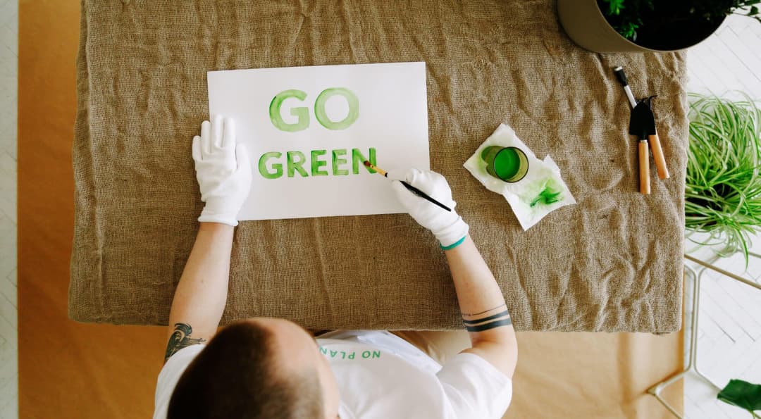 Man painting the words Go Green on paper.