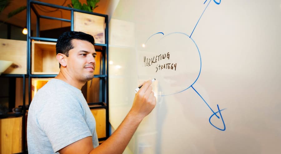 Man at whiteboard with a pen, creating a marketing strategy
