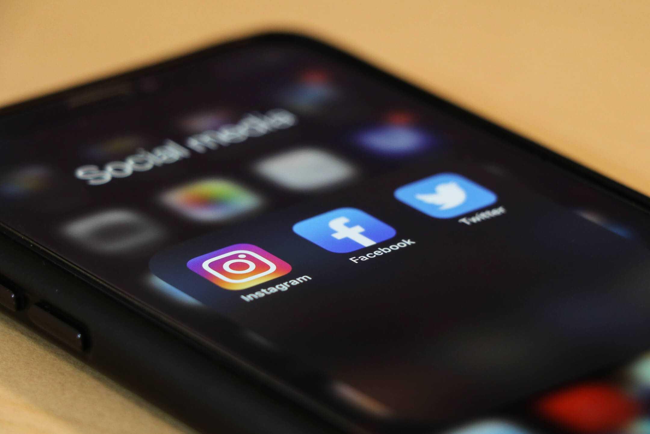 iPhone with Social Media folder open, showing Instagram, Facebook and Twitter.